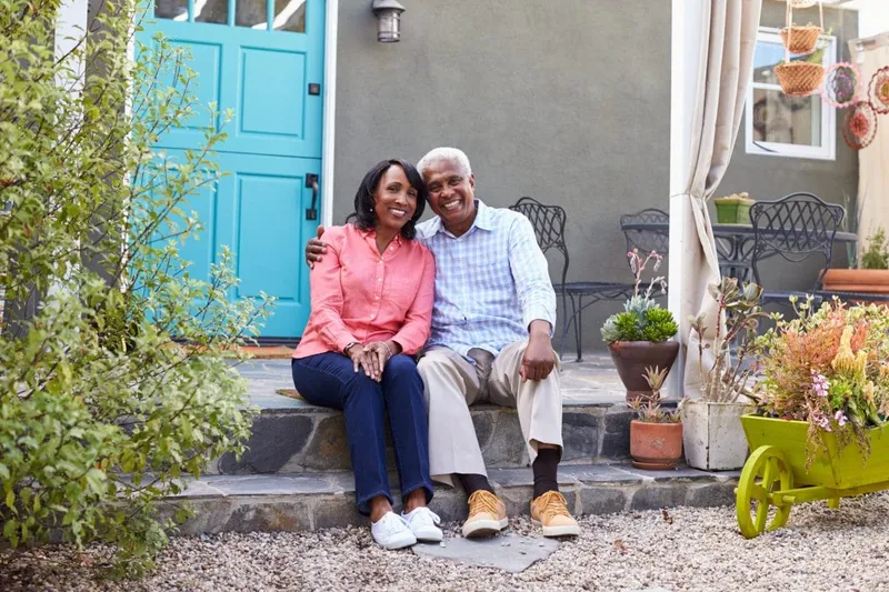 A senior couple sitting on their front porch with plants and patio furniture