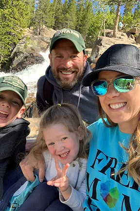 Client Tammy, woman and man with their children, smiling, with sunglasses, outdoors, facing camera