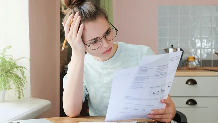 Stressed young woman with glasses, studying studen loan paperwork