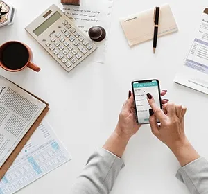 manos usando una computadora portátil en el escritorio con calculadora, bolígrafo y billetes