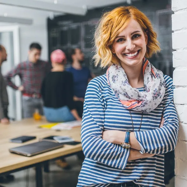 Mujer sonriente con pelo corto y pelirrojo, con una camisa de rayas horizontales.