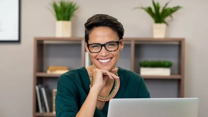 Mujer con gafas trabajando en casa sonriendo a la cámara