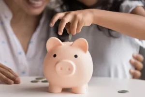 Mom taught daughter to save some money in piggy bank.