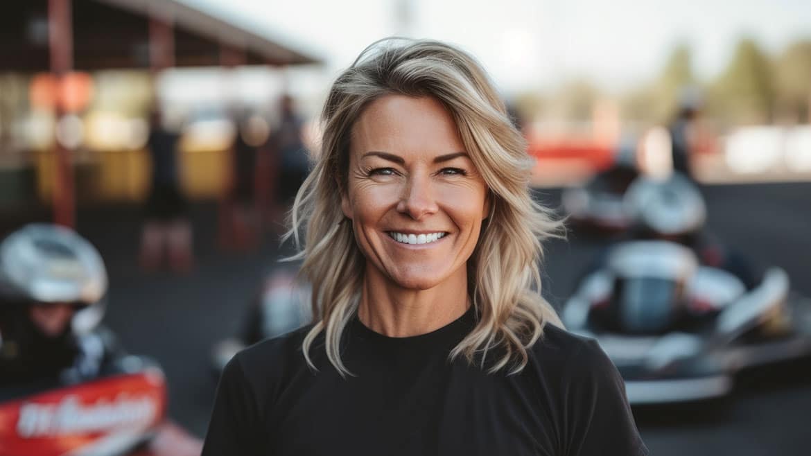 Mujer rubia de mediana edad parada frente a una pista de carreras.